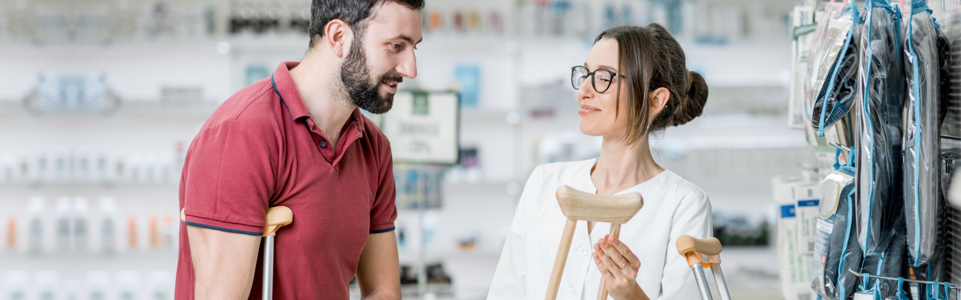woman pharmacist helping to choose crutches for the man